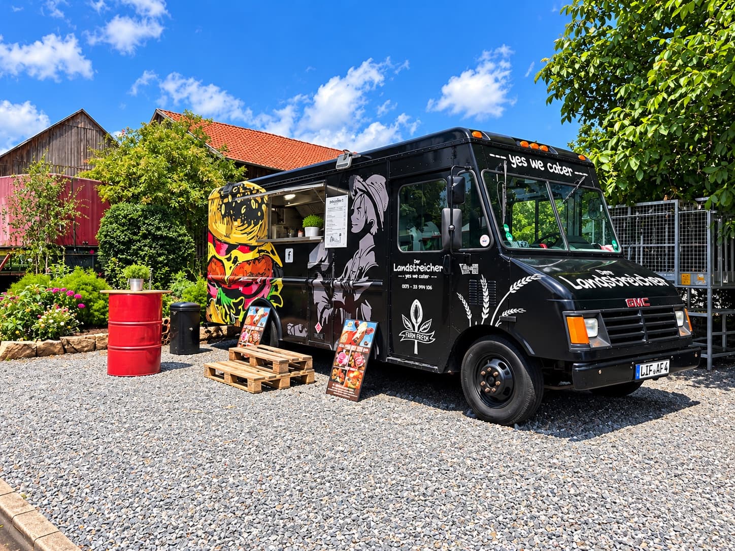 Der schwarze Landstreicher-Foodtruck mit Burger-Graffiti auf einem Kiesplatz bei blauem Himmel